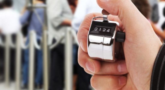 Hand held tally counter counting headcount of people in a queue