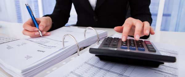 Midsection of businesswoman calculating tax at office desk