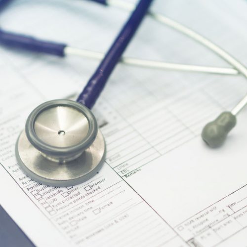 Stethoscope prescribing treatment to patient for doctor with pen writing recipe on clipboard in hospital.